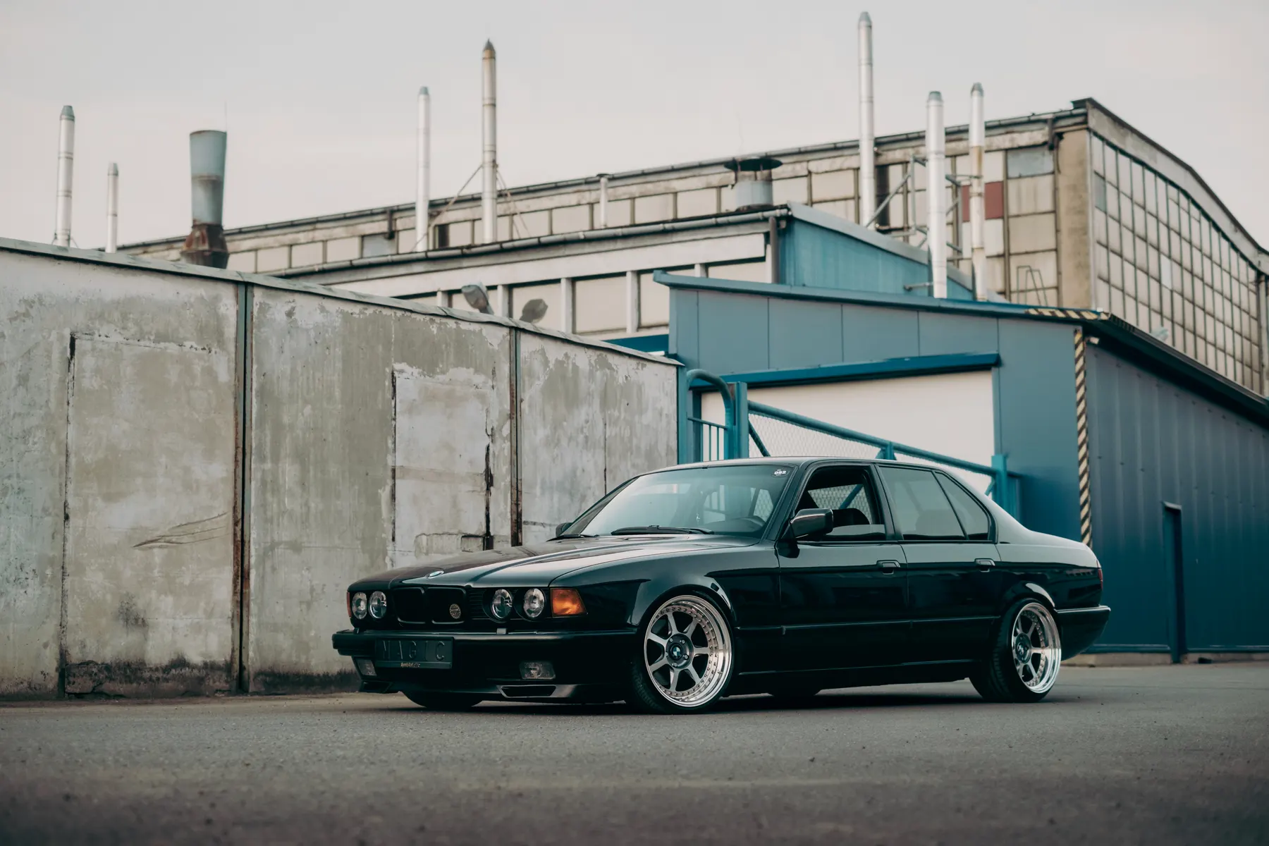 Neon yellow widebody BMW M3 outside modern office building
