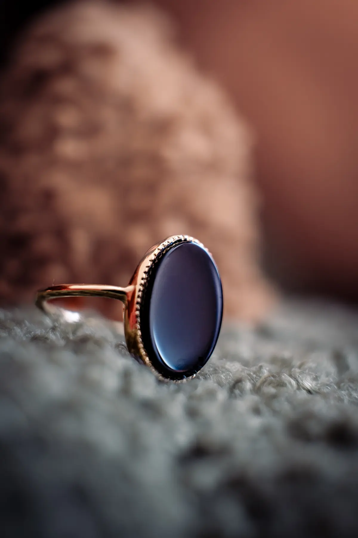 Gold ring with black onyx stone on textured fabric